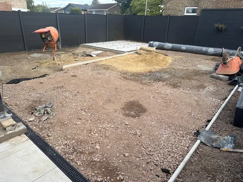 Garden groundworks under way, with a drainage channel, a pipe run and a cement mixer