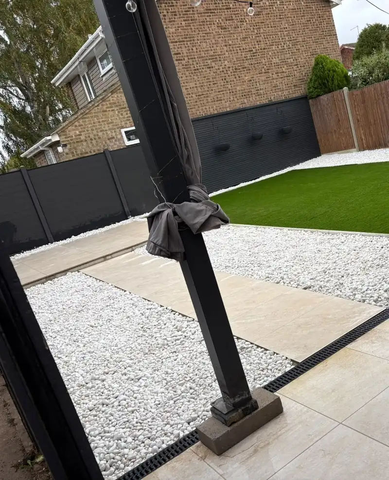 The same garden finished, with porcelain paving, white gravel, a drainage channel and artificial lawn