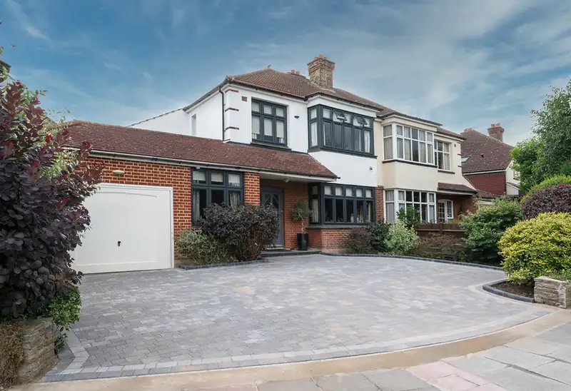 Block paved driveway curving in front of a brick semi-detached house