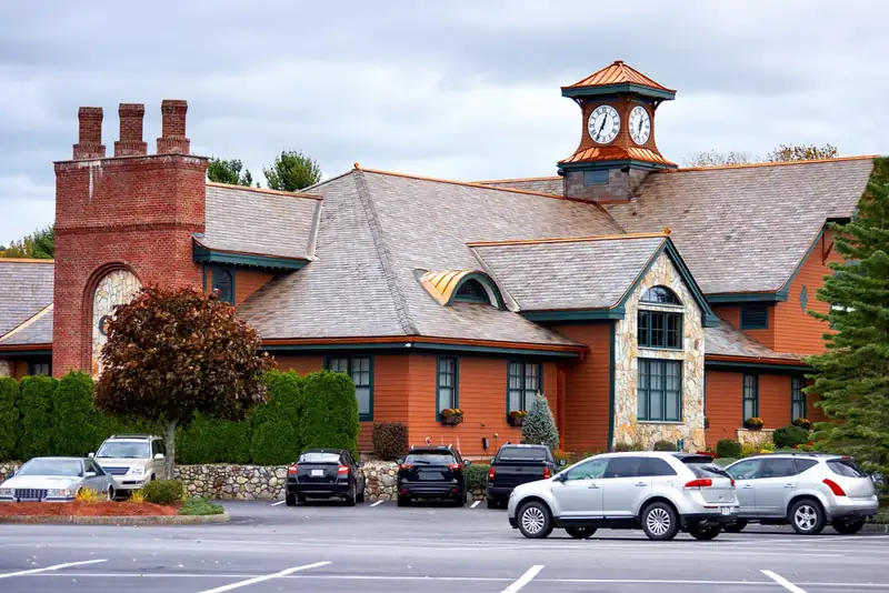 Large clubhouse building with a clock tower and a tarmac car park in front