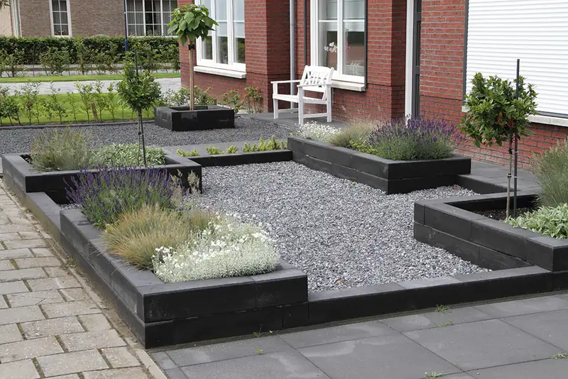 Front garden with black sleeper raised beds, gravel and planting
