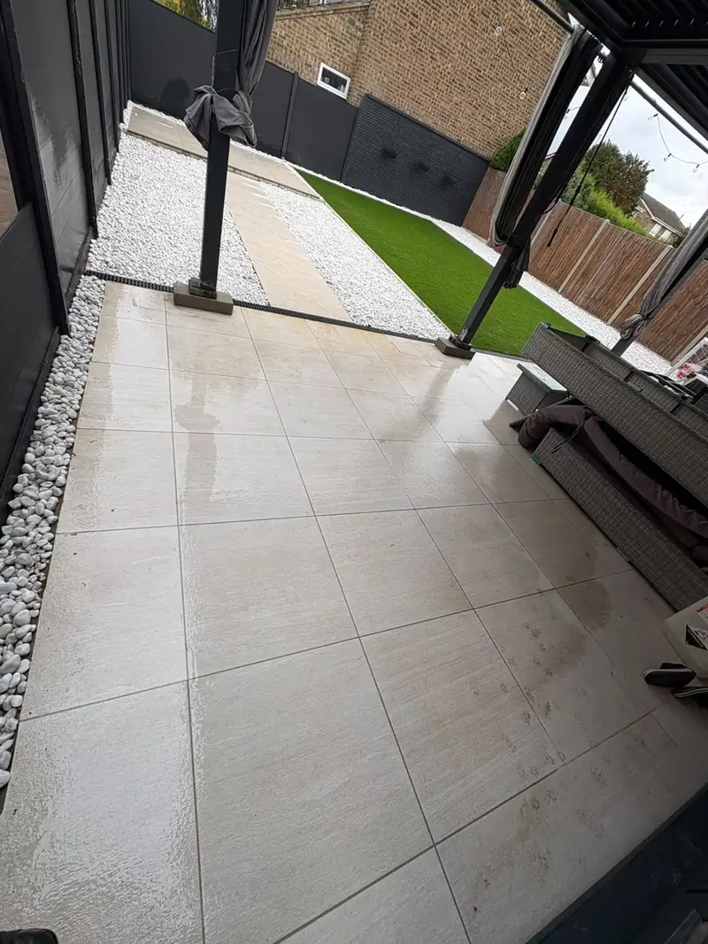 Large porcelain patio slabs leading to white gravel and a lawn
